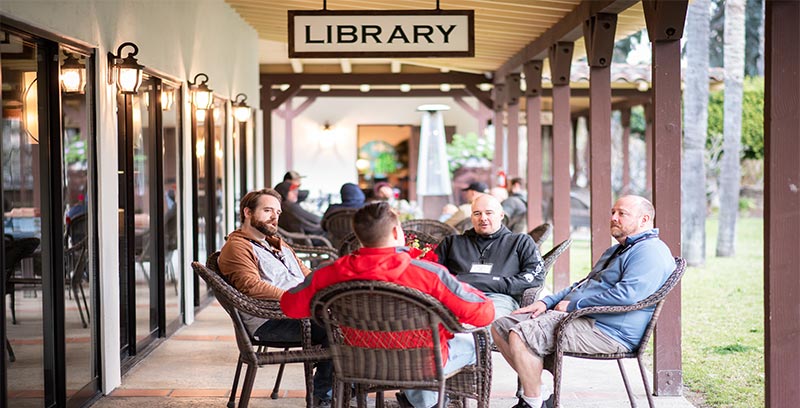 a group of men sitting at tables outside a library